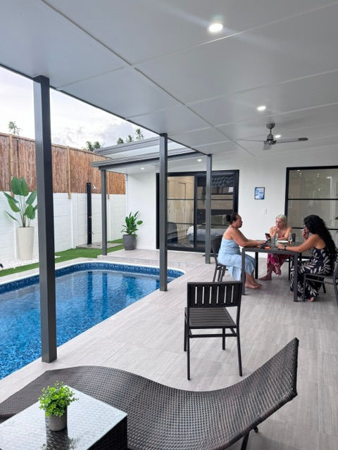 Three guests seated at a villa patio table overlooking their private pool at Le Ama Luxury Villas in Samoa.