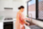 Woman in striped dress washing dishes in bright kitchen