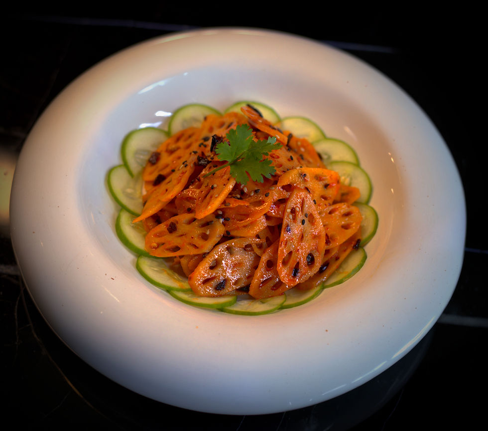 Lotus root salad with sesame seeds on a white plate, garnished with cilantro, cucumber slices. Bright, appetizing colors on dark background.