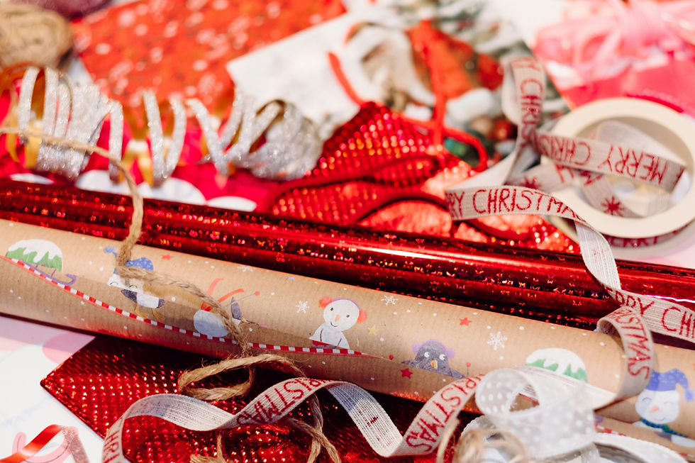 Festive wrapping scene with red, glittery paper, snowman-themed roll, and Merry Christmas ribbons. Joyful holiday mood.