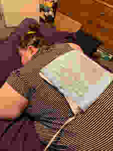 Melissa of Disabled Disney laying down with a heating pad