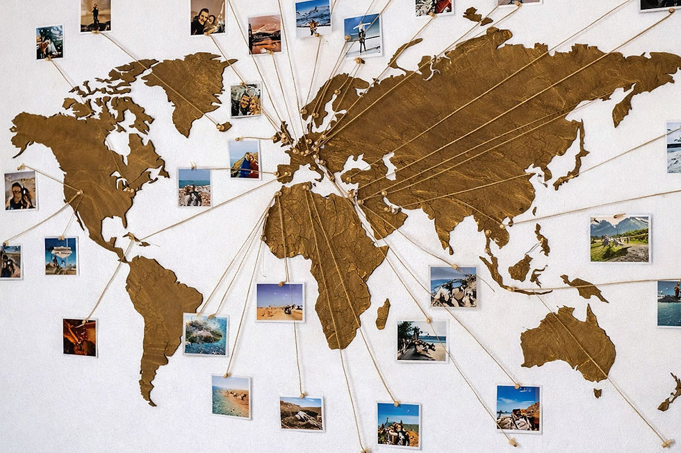 Carte du monde dorée sur mur blanc avec photos reliées par des ficelles. DIY