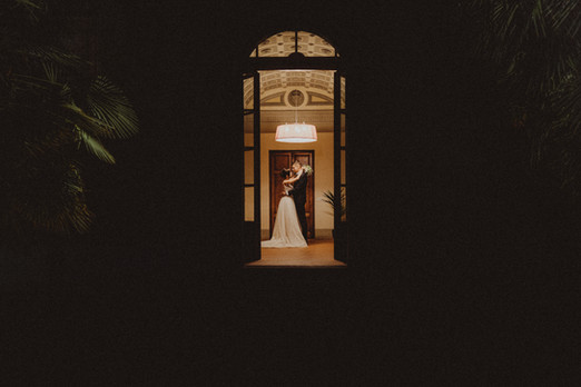 Coppia di sposi balla in una porta, luce splendente, abito bianco, serata romantica.