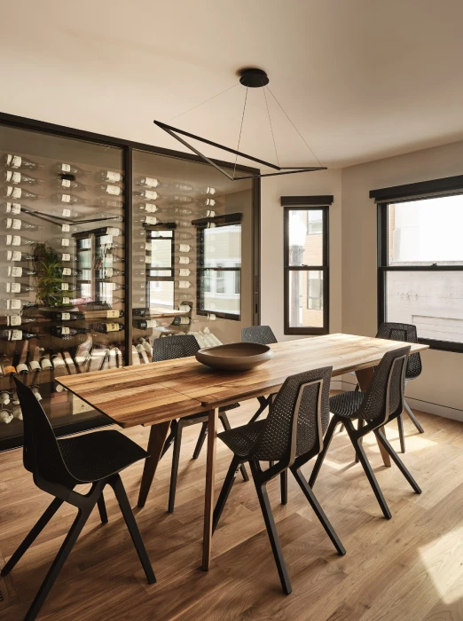 Modern dining room in San Francisco Bay Area with walnut dining table, custom glass wine wall, and contemporary lighting.