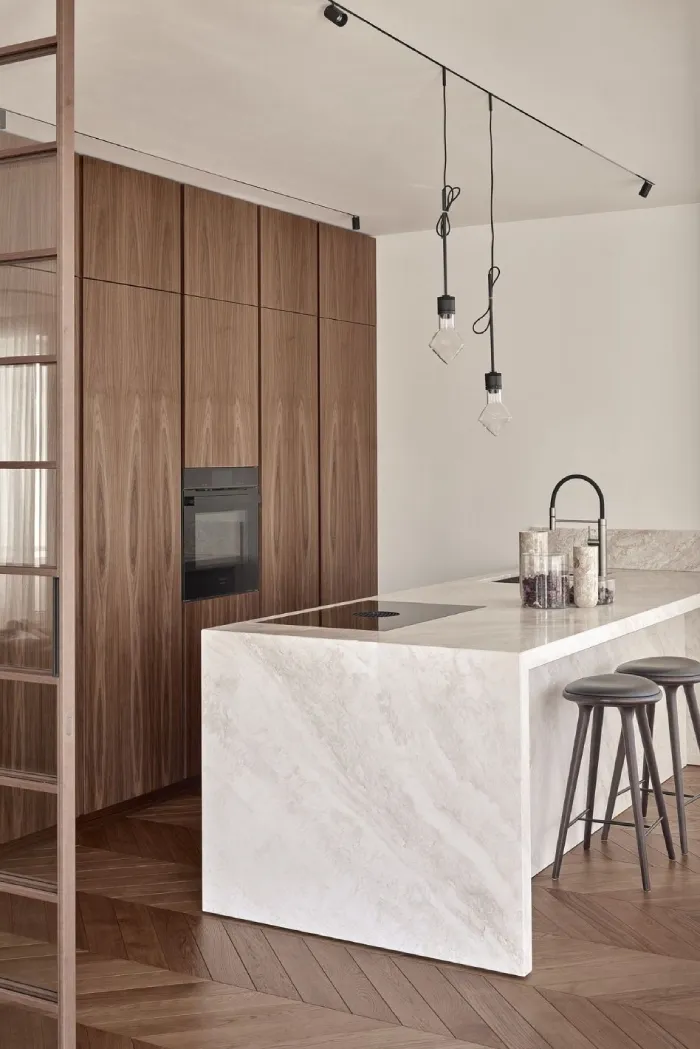 Luxury European kitchen with natural stone waterfall kitchen island and contemporary wood cabinetry.