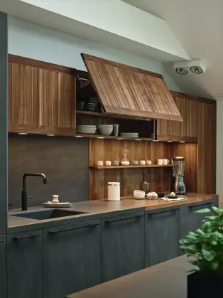 Modern European kitchen with wood cabinetry, dark island, and integrated appliances in a minimalist layout