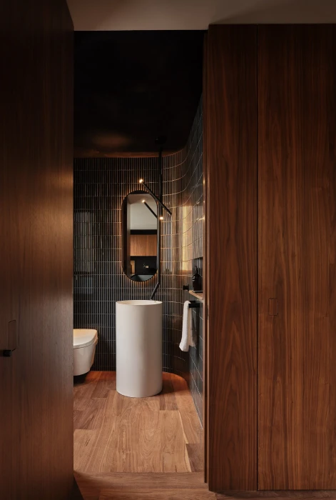 Modern kitchen in San Francisco Bay Area with custom cabinetry, walnut paneling, matte black cabinets, and integrated powder room.