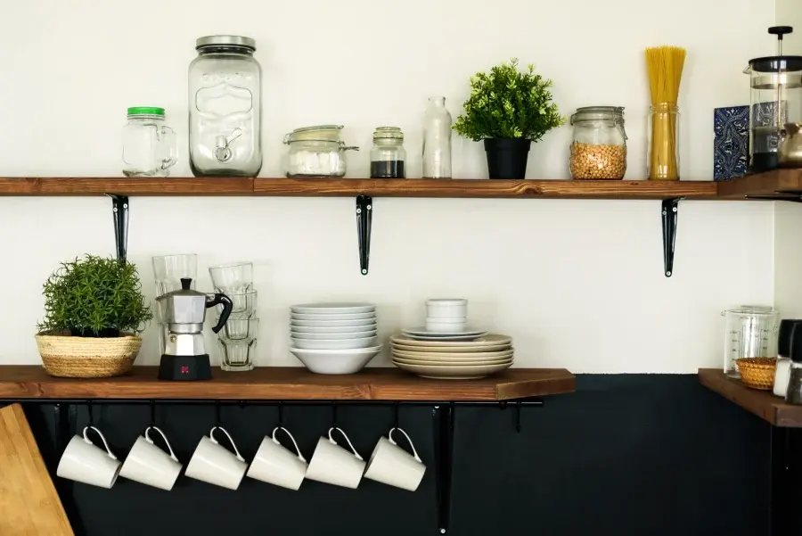 Rustic open kitchen shelves displaying dishes, jars, and cookware in a real-life kitchen setting