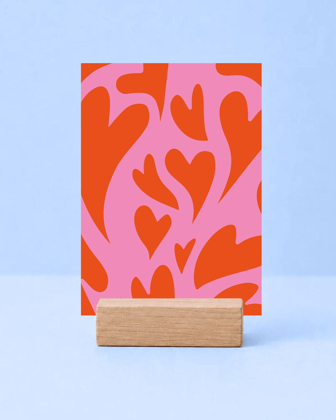 Eine moderne Postkarte mit einem auffälligen Muster aus großen und kleinen orangefarbenen Herzen auf pinkem Hintergrund im ve