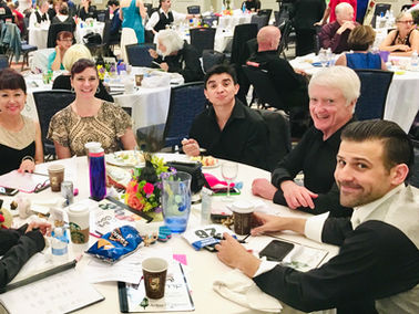 Dan Logan seated with fellow ballroom dance students at a showcase event, reflecting the supportive community he found through dance.