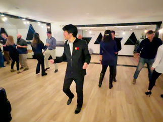 Guided by ReKindle instructor, Matthew, students dancing Swing at Studio Uplift, learning a fun move together.