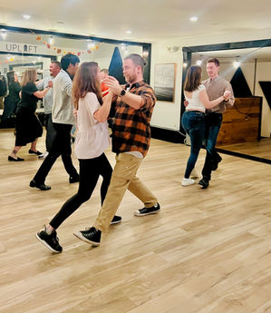 A group of students dancing Waltz at Studio Uplift, learning a fun move together.