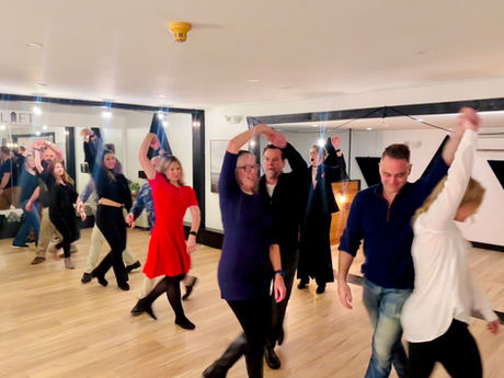 A group of students dancing Swing at Studio Uplift, learning a fun move together.
