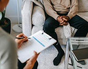 A clinician filling out a mental health screening assessment form on a clipboard at Telos Mental Wellness.