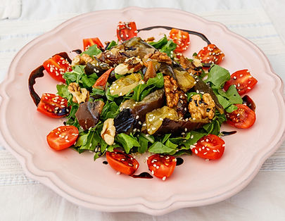 Fresh salad with leafy greens, cherry tomatoes, walnuts, sesame seeds, and balsamic dressing.