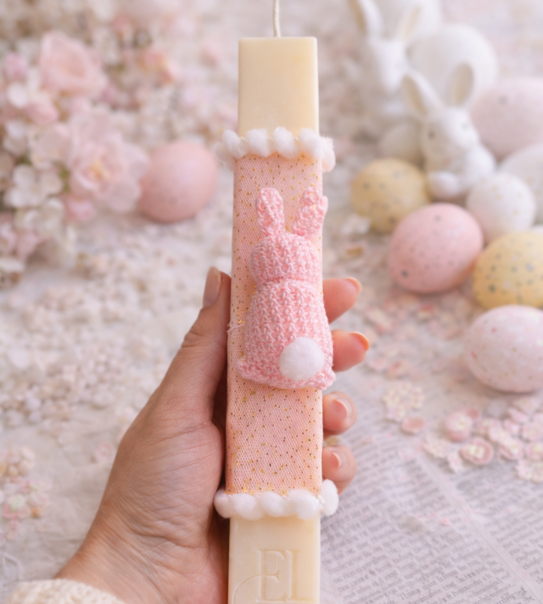 Handmade scented soy Easter candle decorated with a pink crochet bunny brooch on a soft Easter-themed background