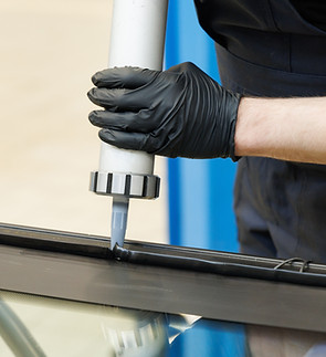 Worker applying an adhesive sealant to car windscreen preparing for replacement__.jpg