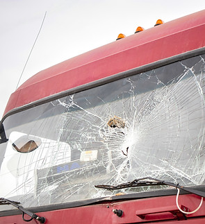 The windshield of a red truck is shattered, showing signs of impact and damage..jpg