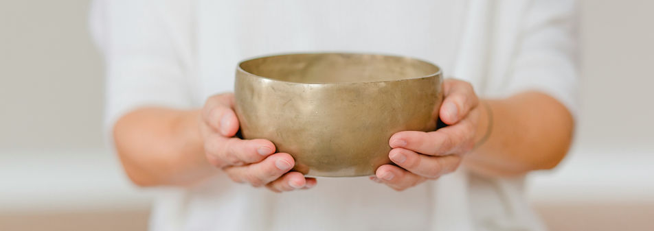 Zwei Hände halten eine Klangschale in der Hand. Die Person, die die Klangschale hält, träg