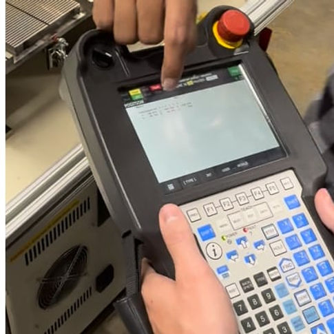 Operator practices CNC machine operation using a handheld pendant during hands-on NEMT training.