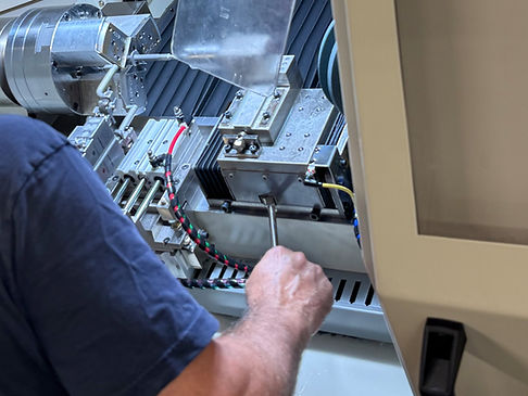 NEMT technician inspects internal mechanical systems during preventive maintenance on a ProGrind CNC grinding machine.