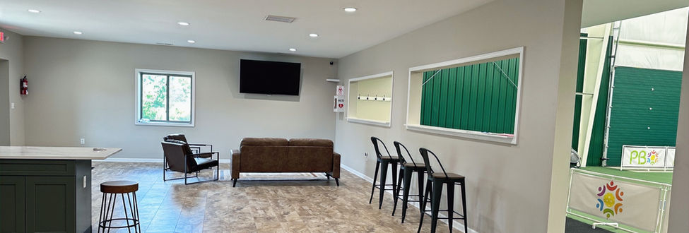 Large indoor room with brown couch and chair and three stools for sitting
