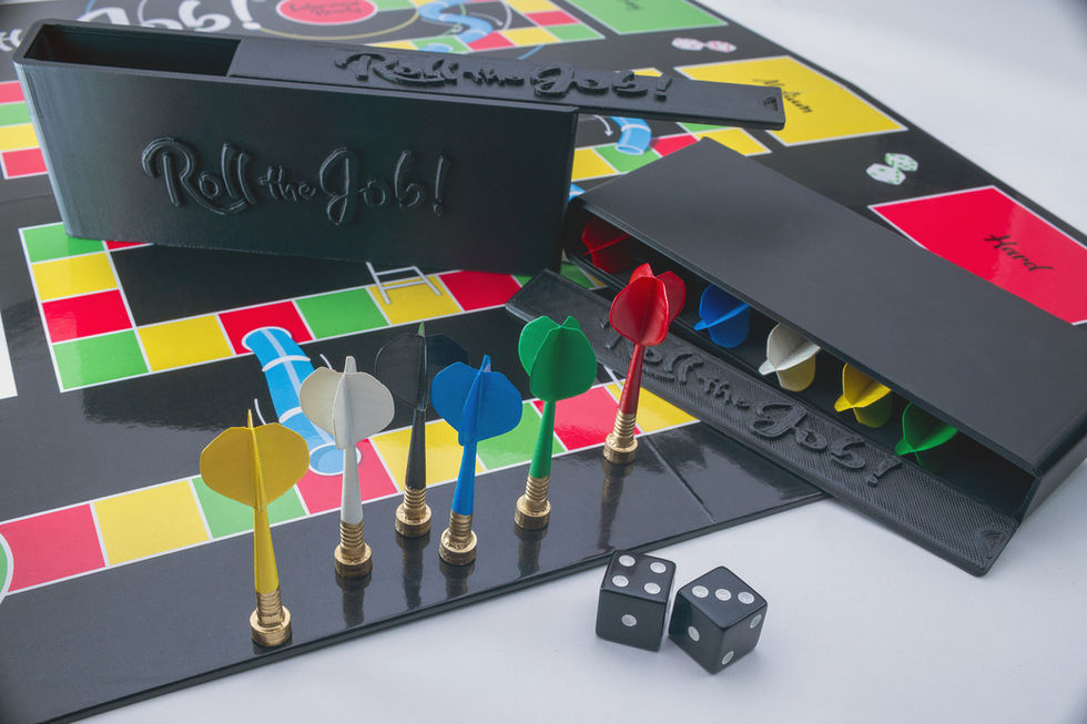 Colorful player pieces lined up on the Roll the Job! interview board game beside the game box and dice.