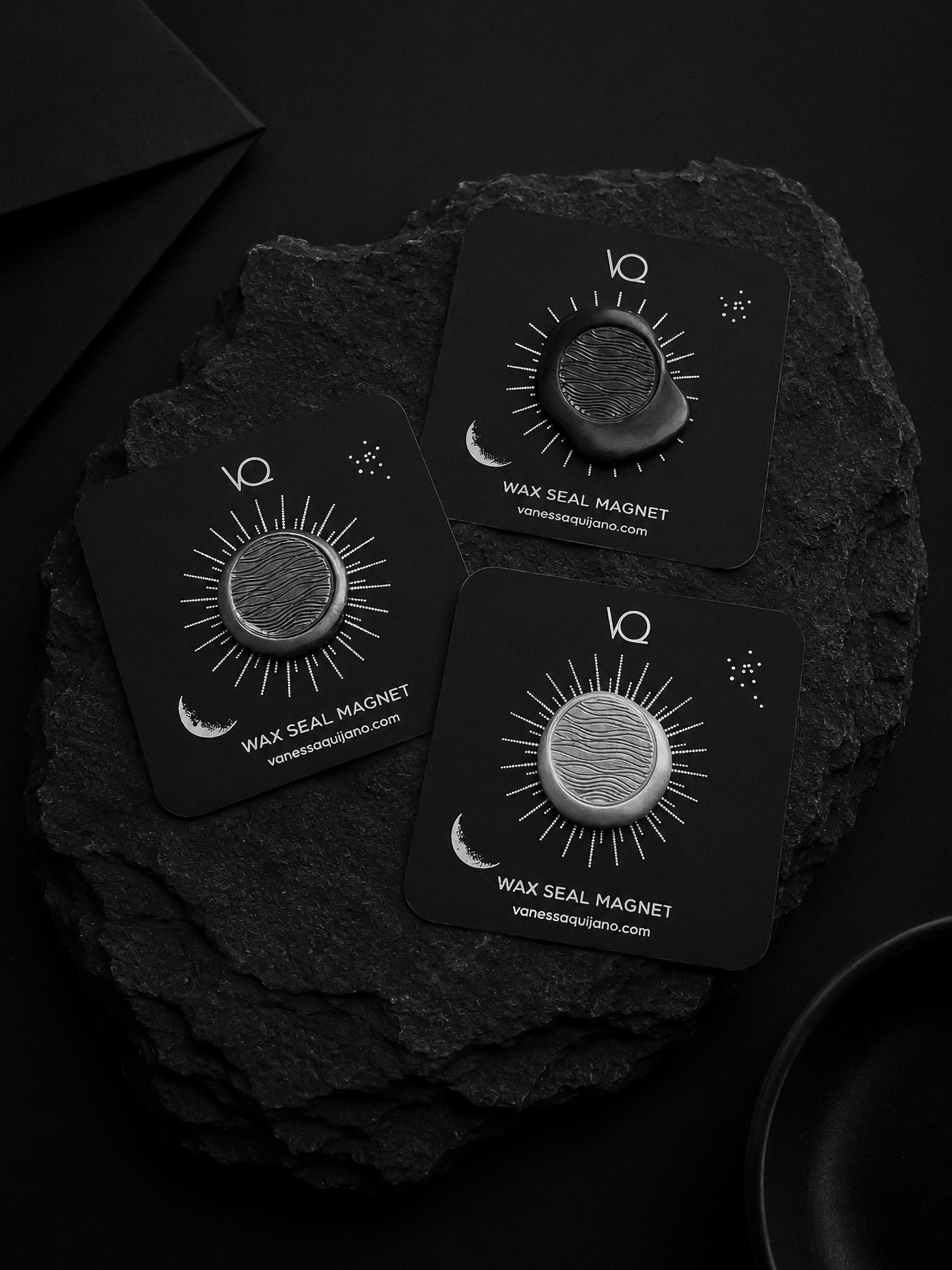Waves wax seal magnet collection featuring Silver, Charcoal and Onyx finishes displayed together on black slate stone.