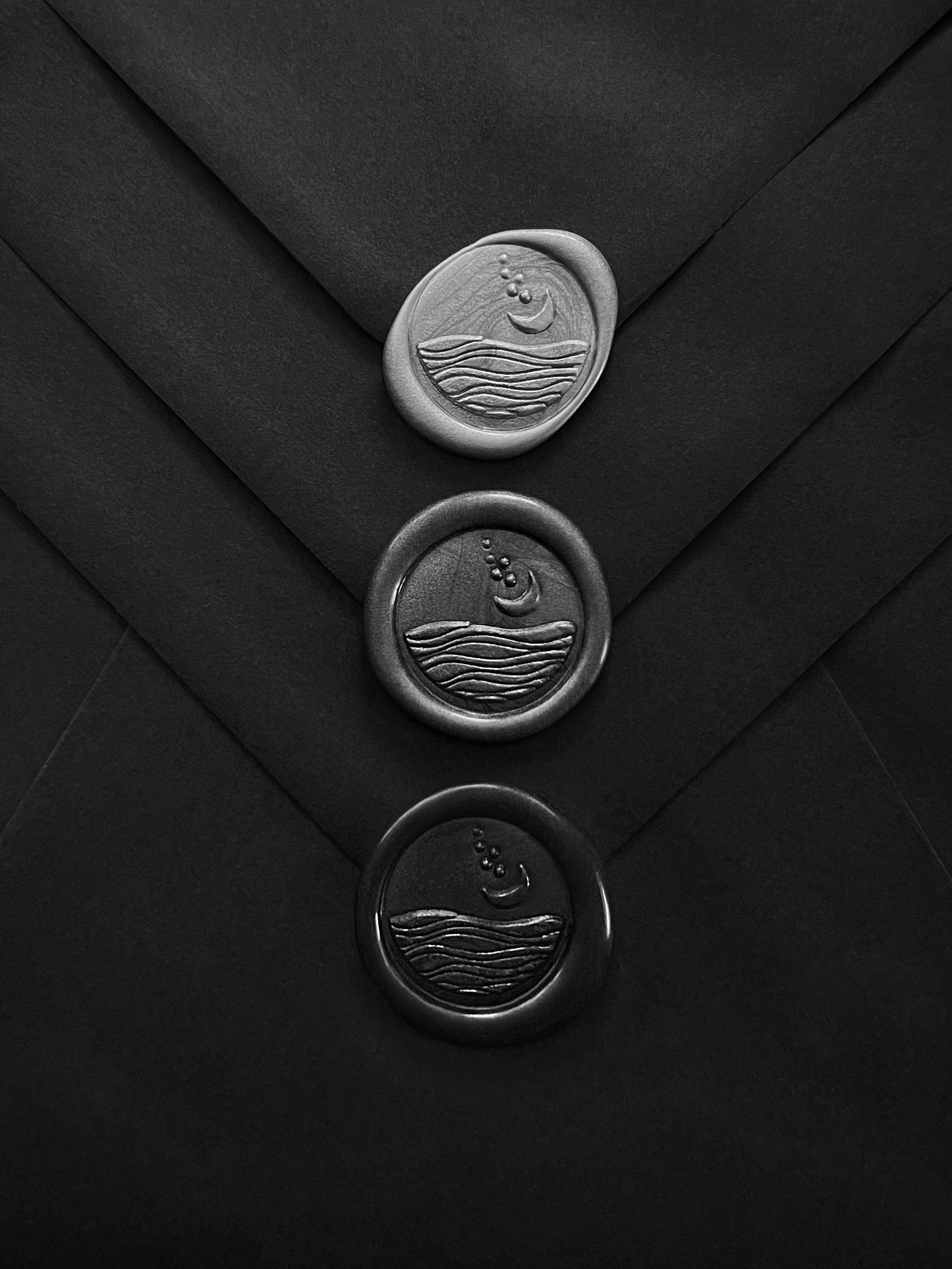 Flat lay of premade wax seals in silver, charcoal, and black tones with self-adhesive backing.