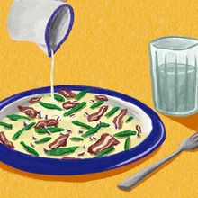 pouring milk over mash potatoe with bacon and green beans with a glass of water on the side