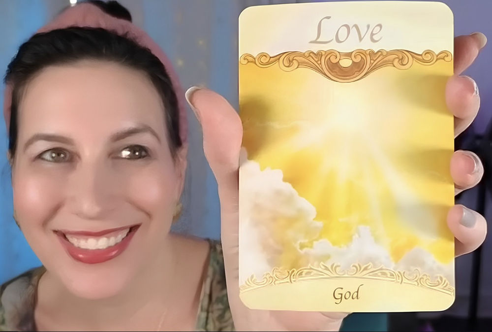 Elysia smiling and holding up the Love oracle card