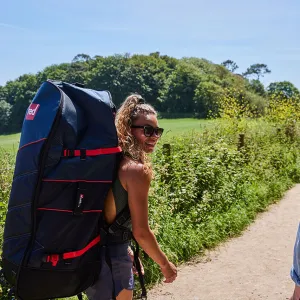 A happy customer walking away from an AdventureCrate with their inflatable paddleboard on their back