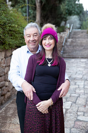 Smiling man with arms around a woman in a pink hat