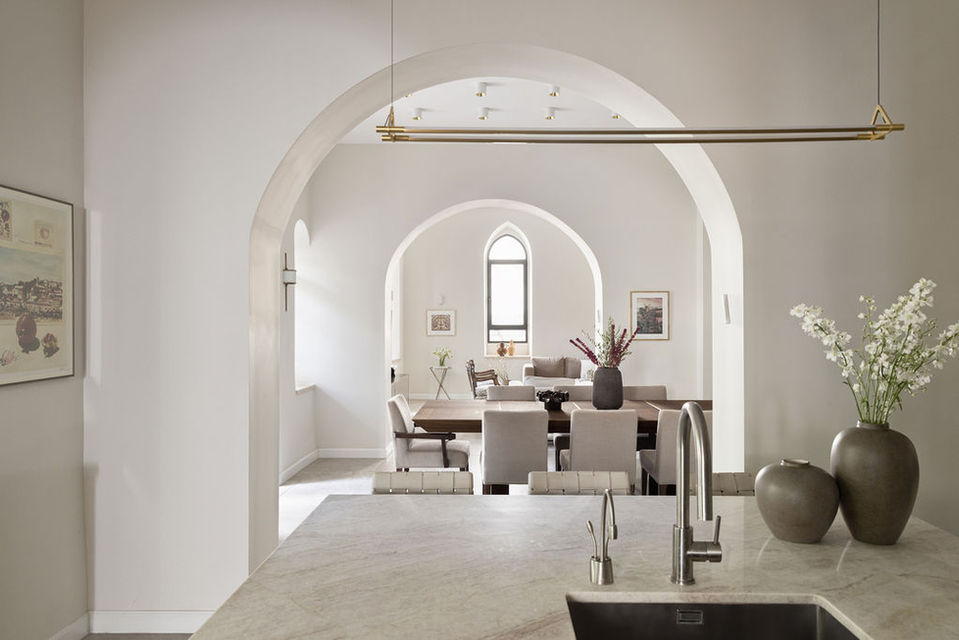 Elegant dining room with archways, table, chairs, and vases. Alyssa Magid Interiors.
