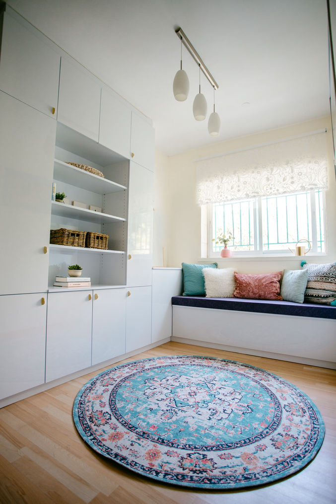 White cabinets, shelves, and a window seat in room with round rug. Alyssa Magid Interiors