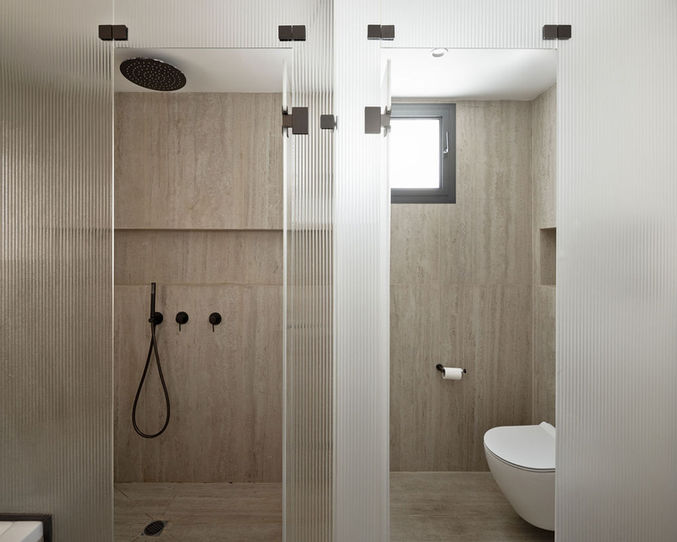 Modern bathroom with glass shower and toilet, neutral colors, minimalist design.