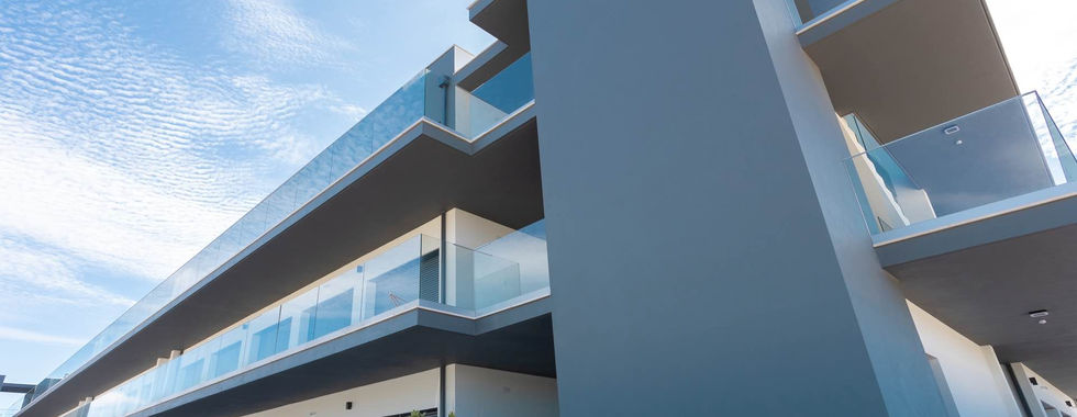 Front of modern building with a blue sky and glass railings on the balconies - - Sunset Views Nazare Apartments