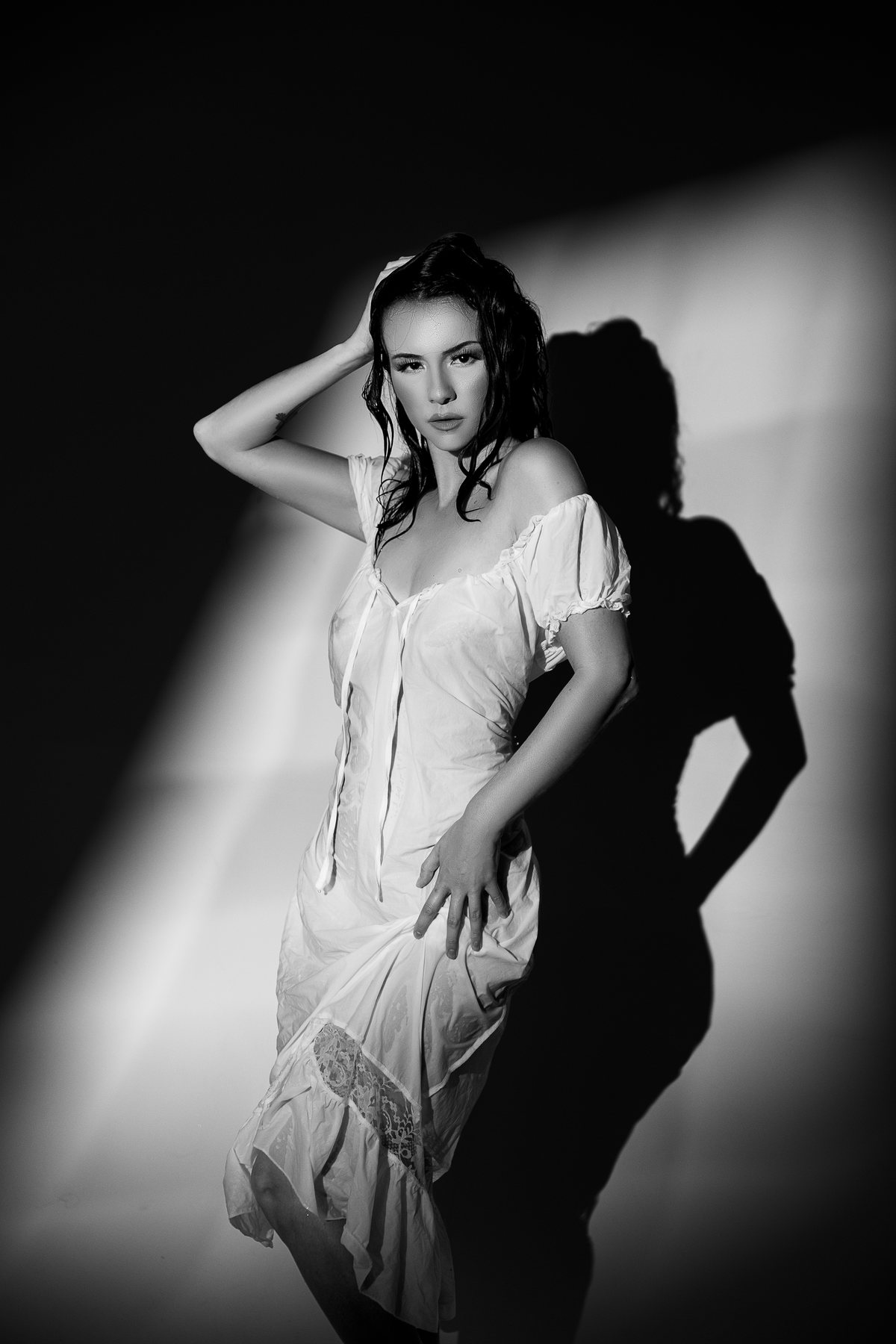 Black and white bridal boudoir portrait of a woman in a white nightgown in soft window light