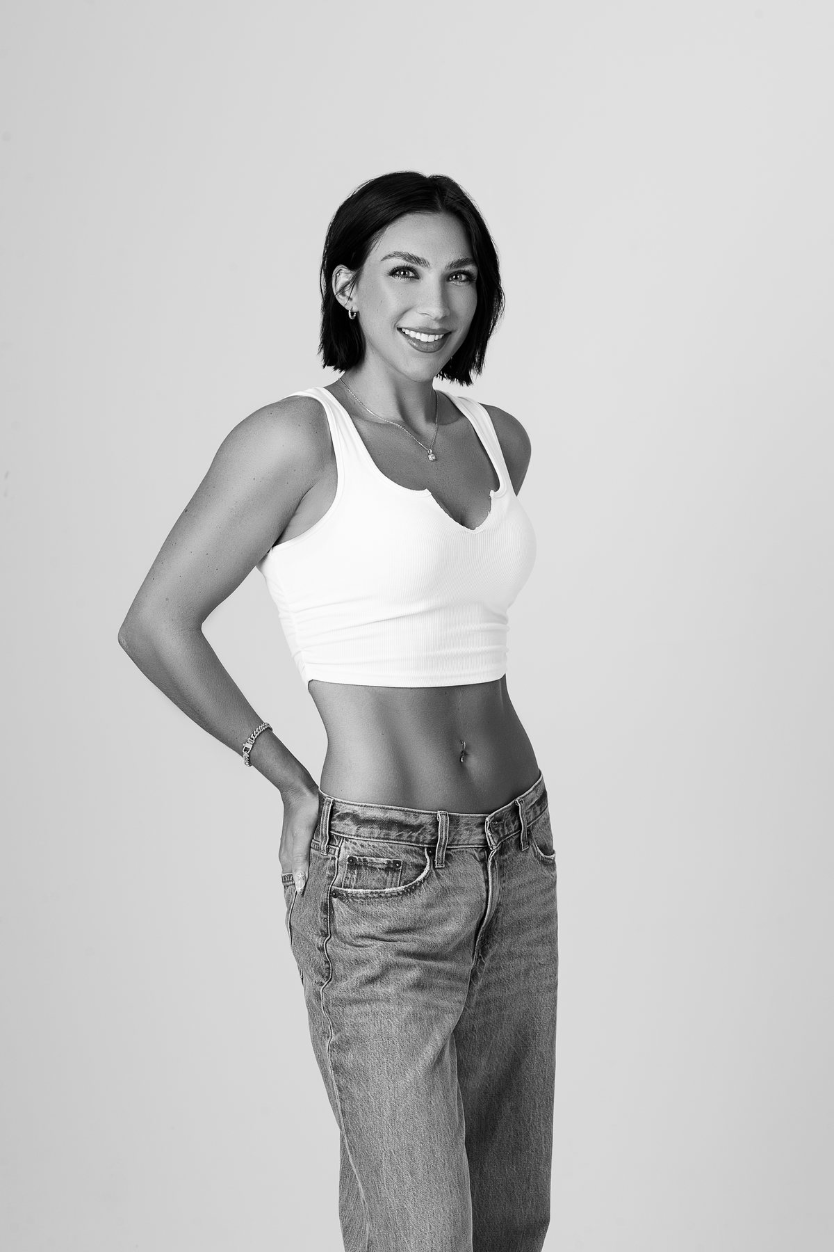 Black and white portrait of a fit woman in a white crop top and jeans