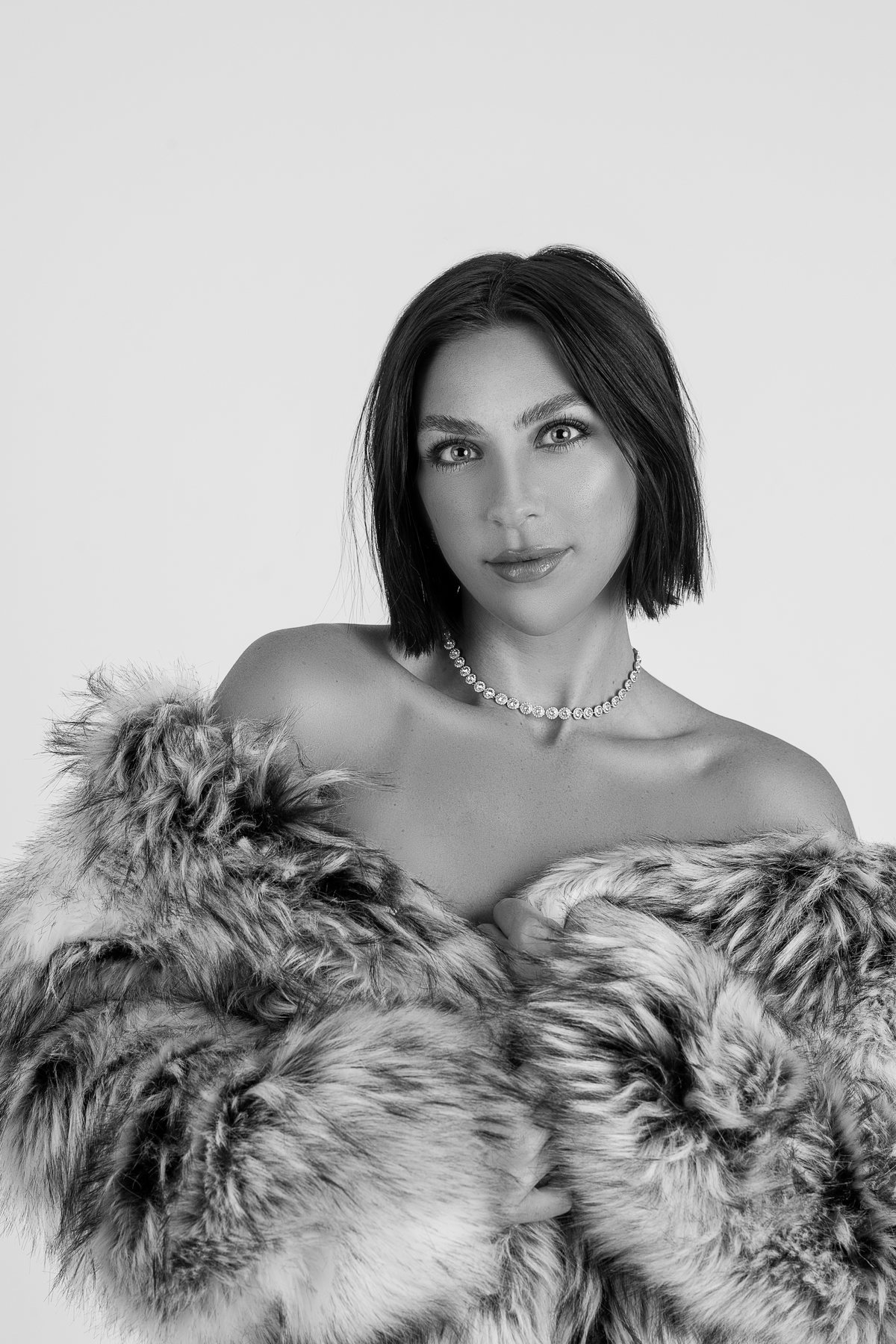 Black and white glamour portrait of a woman in a crystal choker and a fur wrap after professional hair and makeup