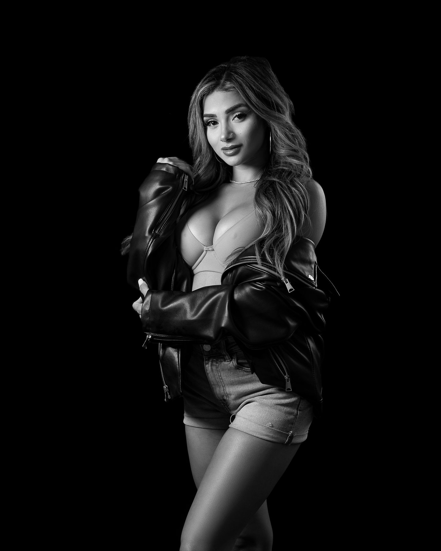 Black and white Austin boudoir portrait of a woman in a leather jacket in low key light