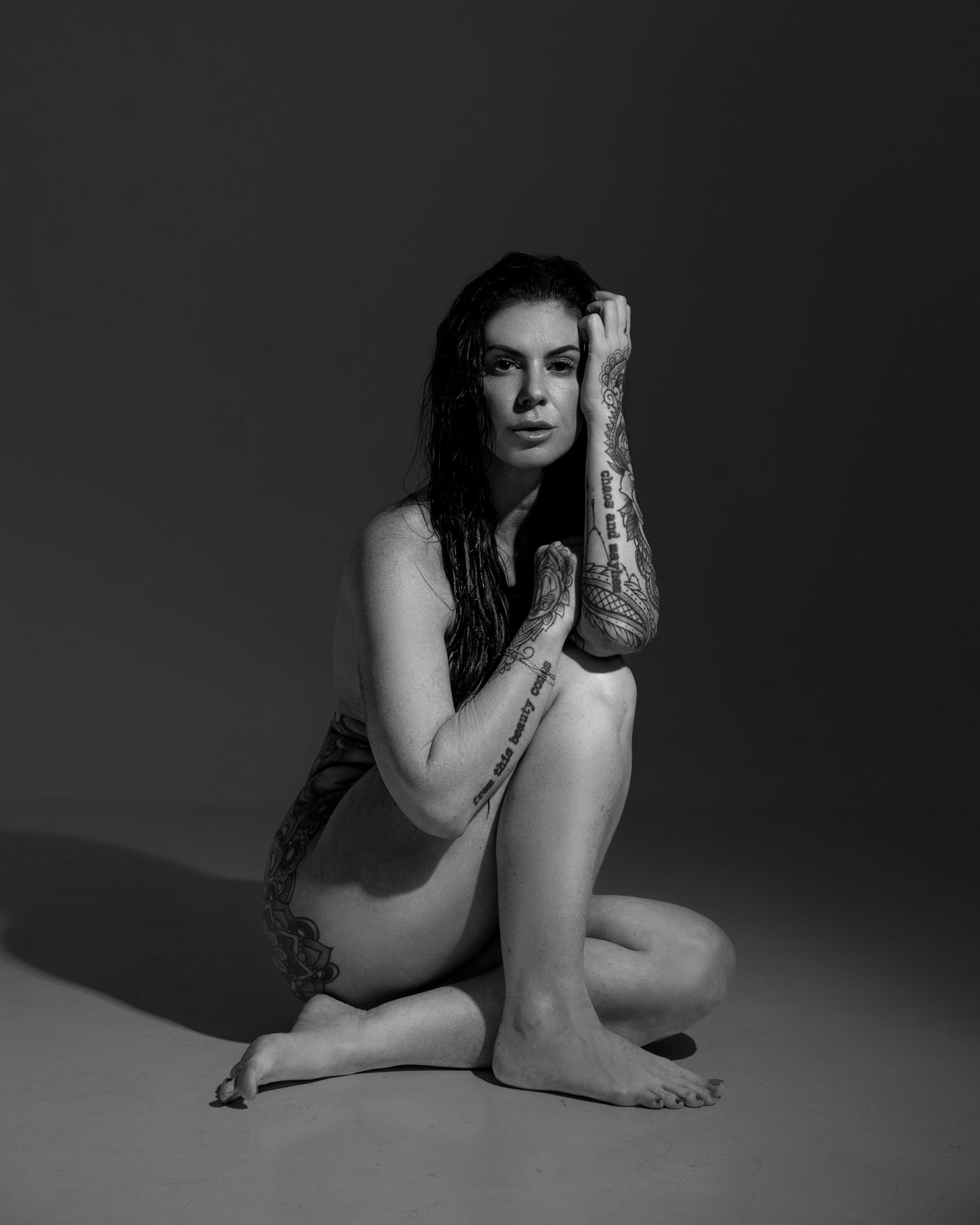 Black and white Austin boudoir portrait of a woman seated on the studio floor in low key light