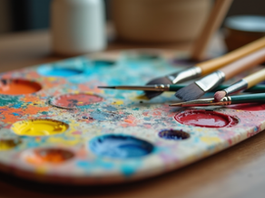 Colorful paint palette with brushes on a wooden table, splattered with vibrant hues of red, yellow, blue, and orange, creating an artistic mood.