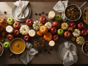 Overhead view of a fall table filled with pumpkin dishes, apples, spices, and candles.