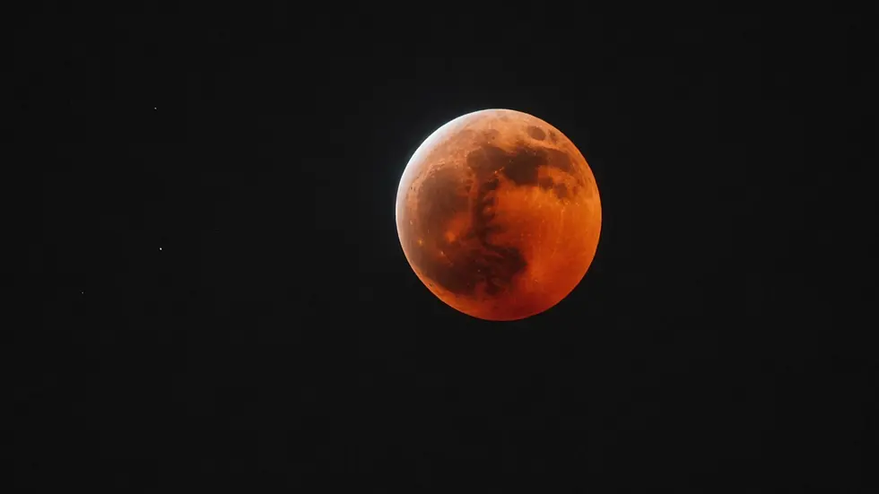 Eye-level view of the lunar eclipse casting a red hue on the moon