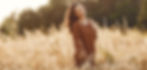 Mujer feliz en un campo de verano al atardecer; transmite calma, libertad y conexión con la naturaleza
