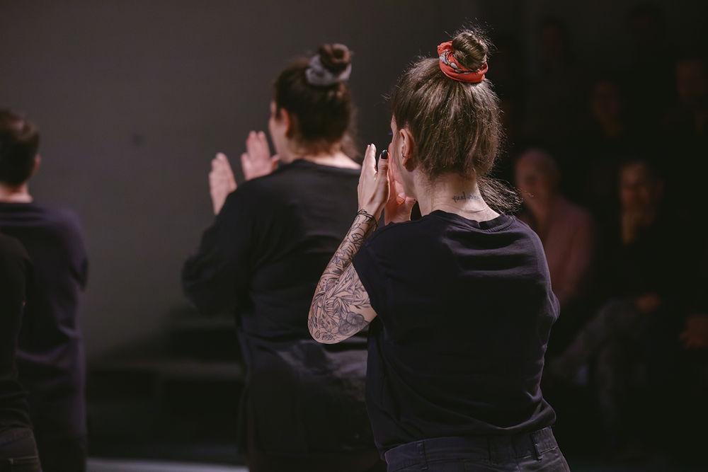 Looking at the backs of two women dressed in black clapping at a Blip Inclusive Multisensory Project.
