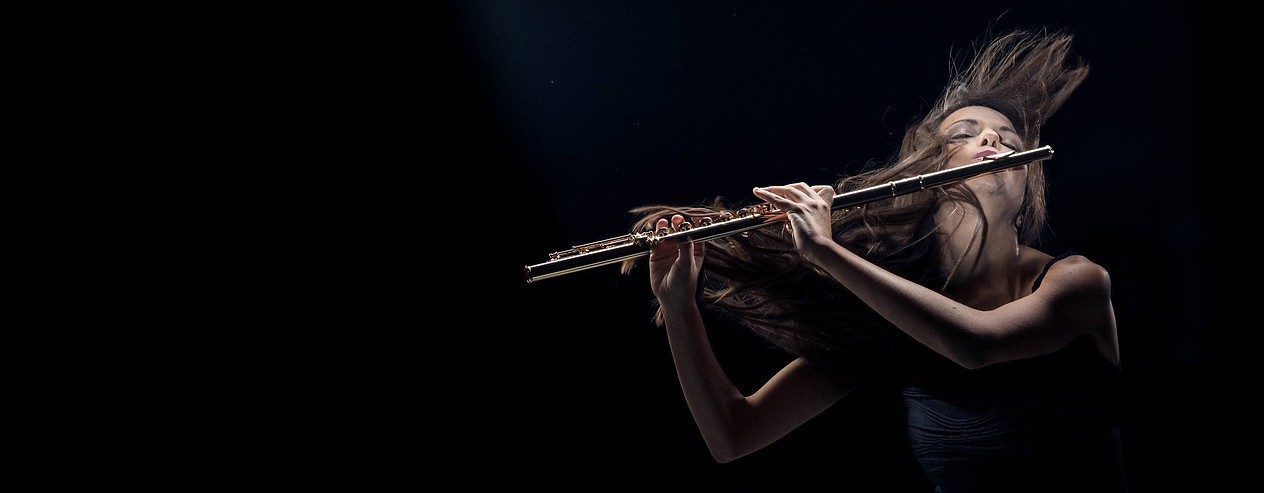 Woman playing her gold flute while flipping her long brown hair backward