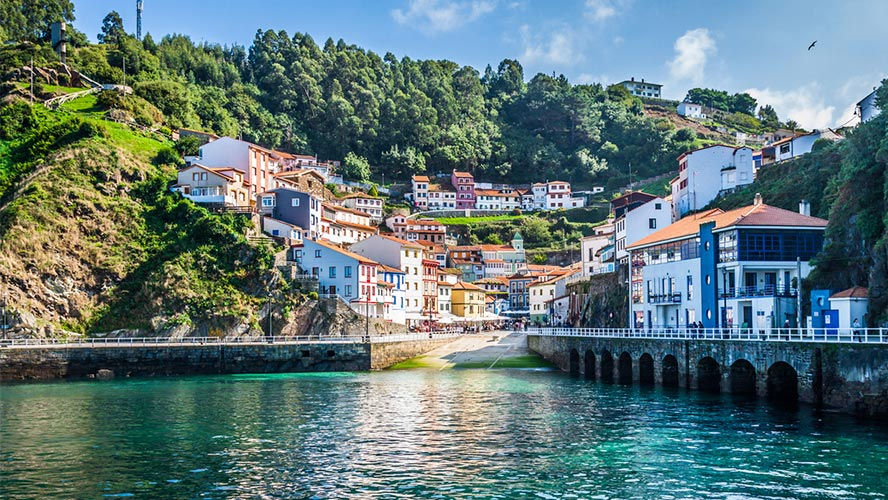 Street-level view of colourful houses rising above the harbour in Cudillero.