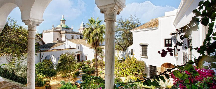 Lush courtyard with white buildings and archways